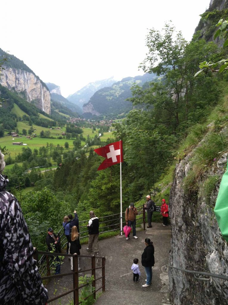 Flag at entrance to Trummelbach Falls with views of waterfalls in the Lauterbrunnen Valley, Switzerland